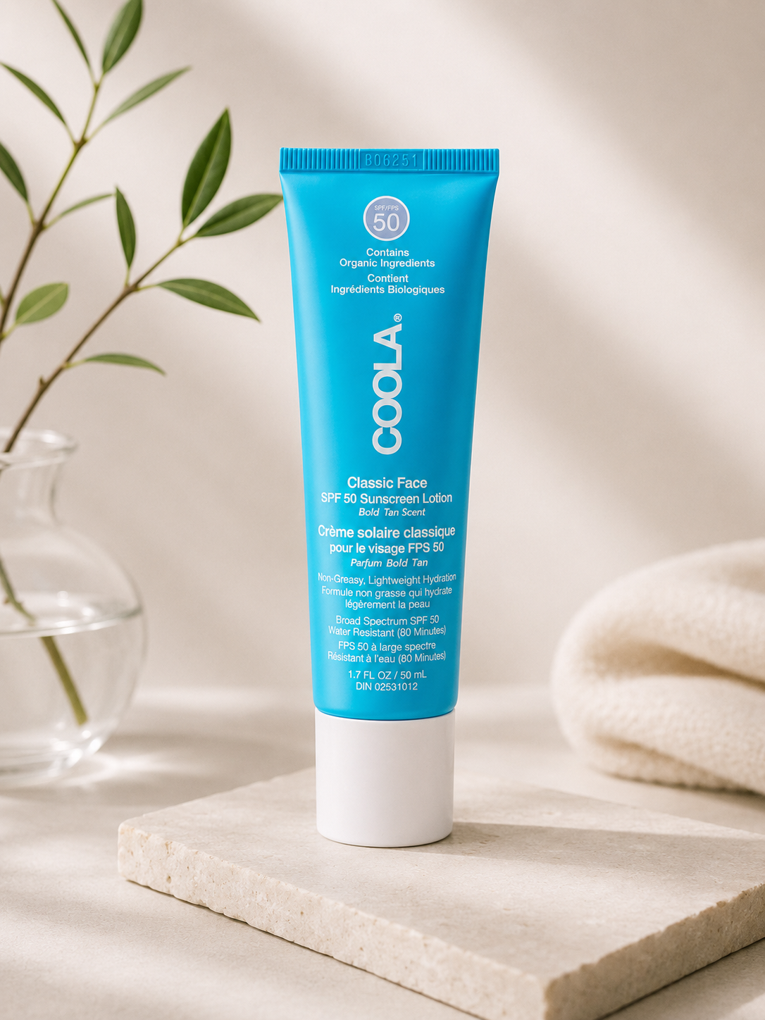 Coola White Tea Face Lotion SPF50 50ml on a light surface with a plant in the background